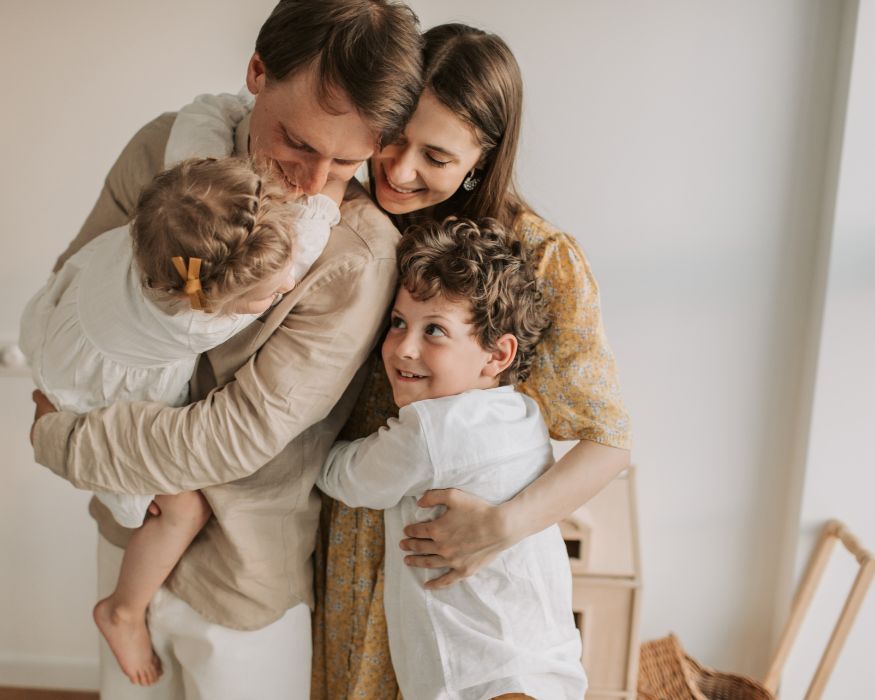 A family embraces in a warm group hug inside their home, symbolizing security and comfort supported by good respiratory health.