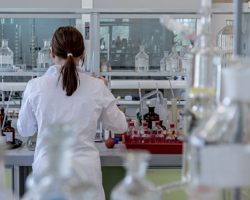 A laboratory professional works among glass equipment and samples, representing AAIC’s commitment to ongoing research and innovation.