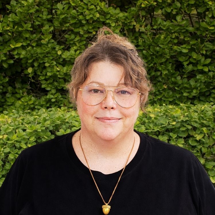 A member of the team wearing glasses and a black shirt with a gold necklace is ready to welcome and support patients.